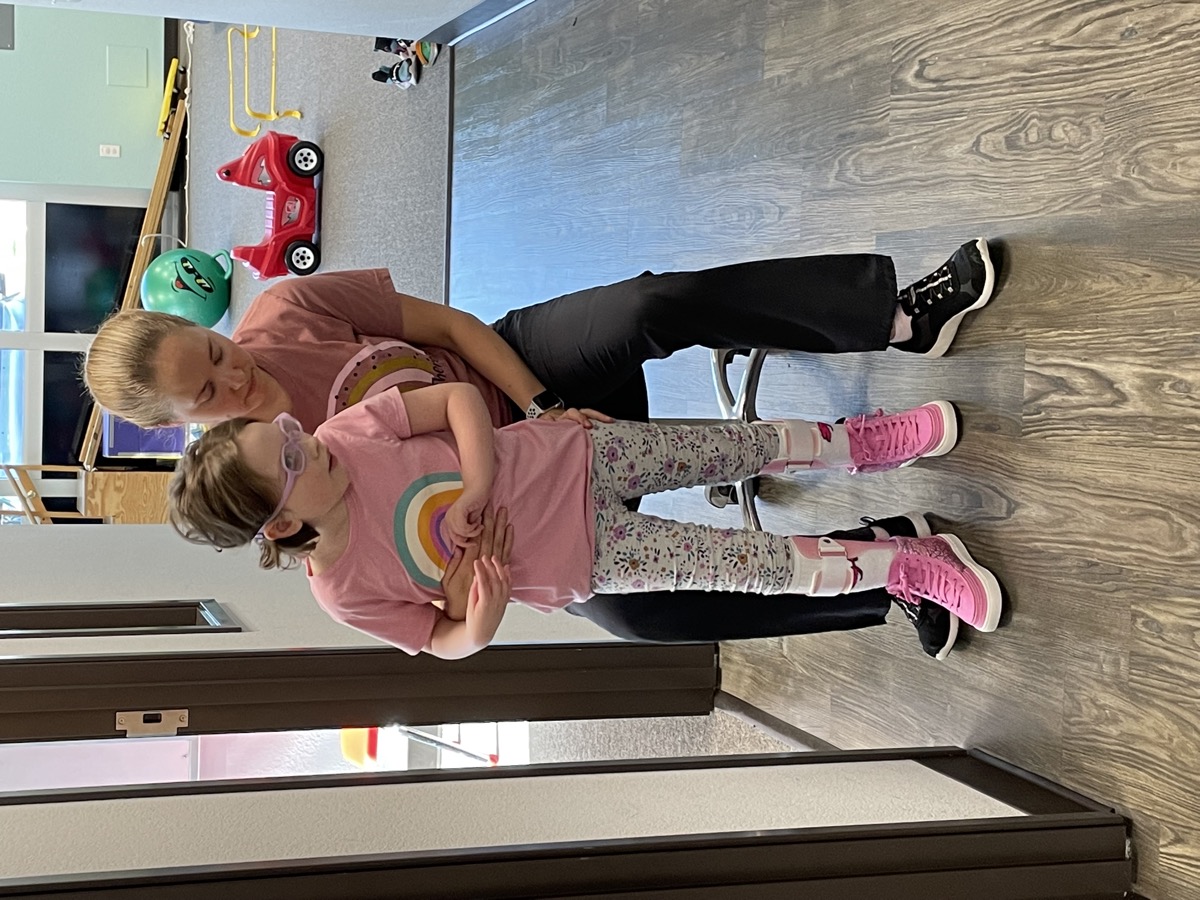 Sophia standing with therapy support in 2022