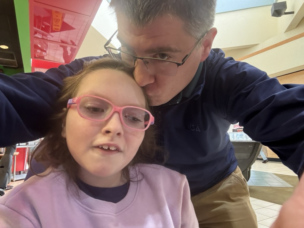 Dad giving Sophia an affectionate kiss during an outing